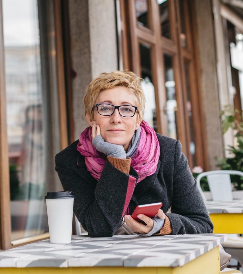 dreamy-woman-with-phone-in-cafe-PMSP74W.jpg